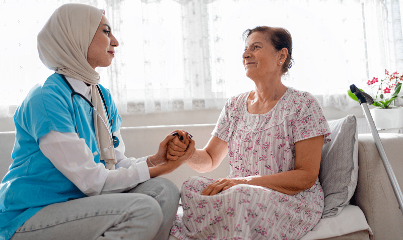 Caregiver comforting elderly woman at home.