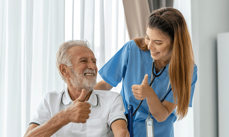 Elderly man and nurse giving thumbs up.