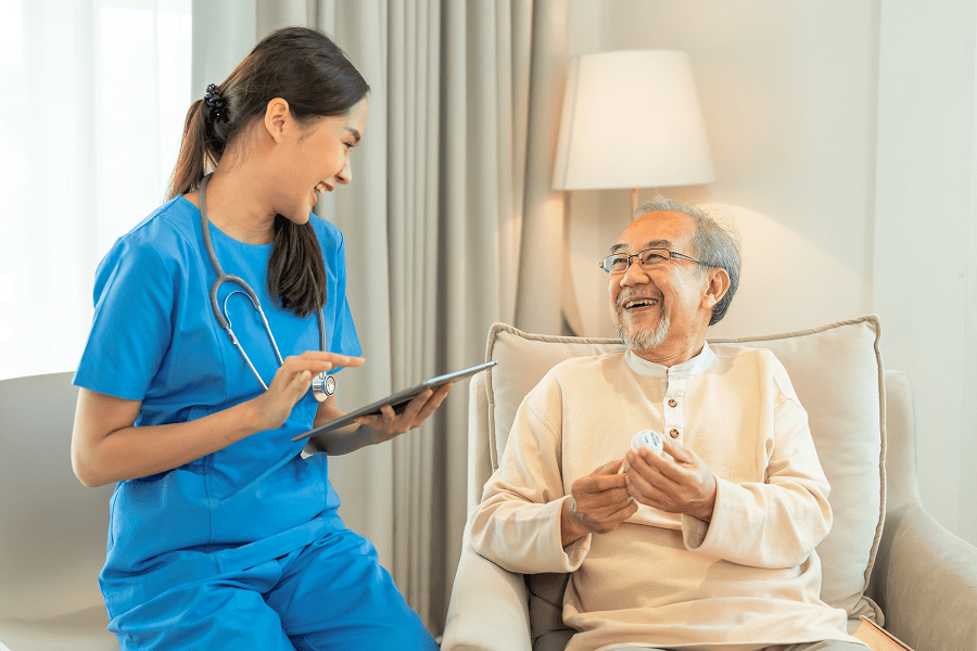 Nurse interacting with smiling elderly patient.