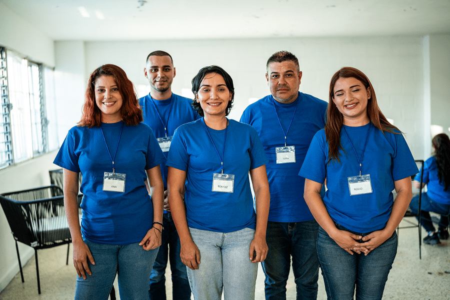 Group of smiling people wearing blue shirts.